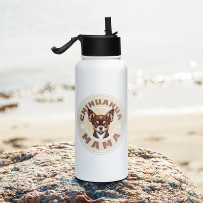 A white insulated water bottle with a black flip-straw lid stands on a large rock with a blurred beach background. The bottle features a circular graphic with the text 'CHIHUAHUA MAMA' and an illustration of a Chihuahua dog.
