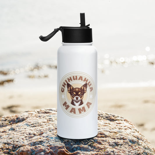 A white insulated water bottle with a black flip-straw lid stands on a large rock with a blurred beach background. The bottle features a circular graphic with the text 'CHIHUAHUA MAMA' and an illustration of a Chihuahua dog.
